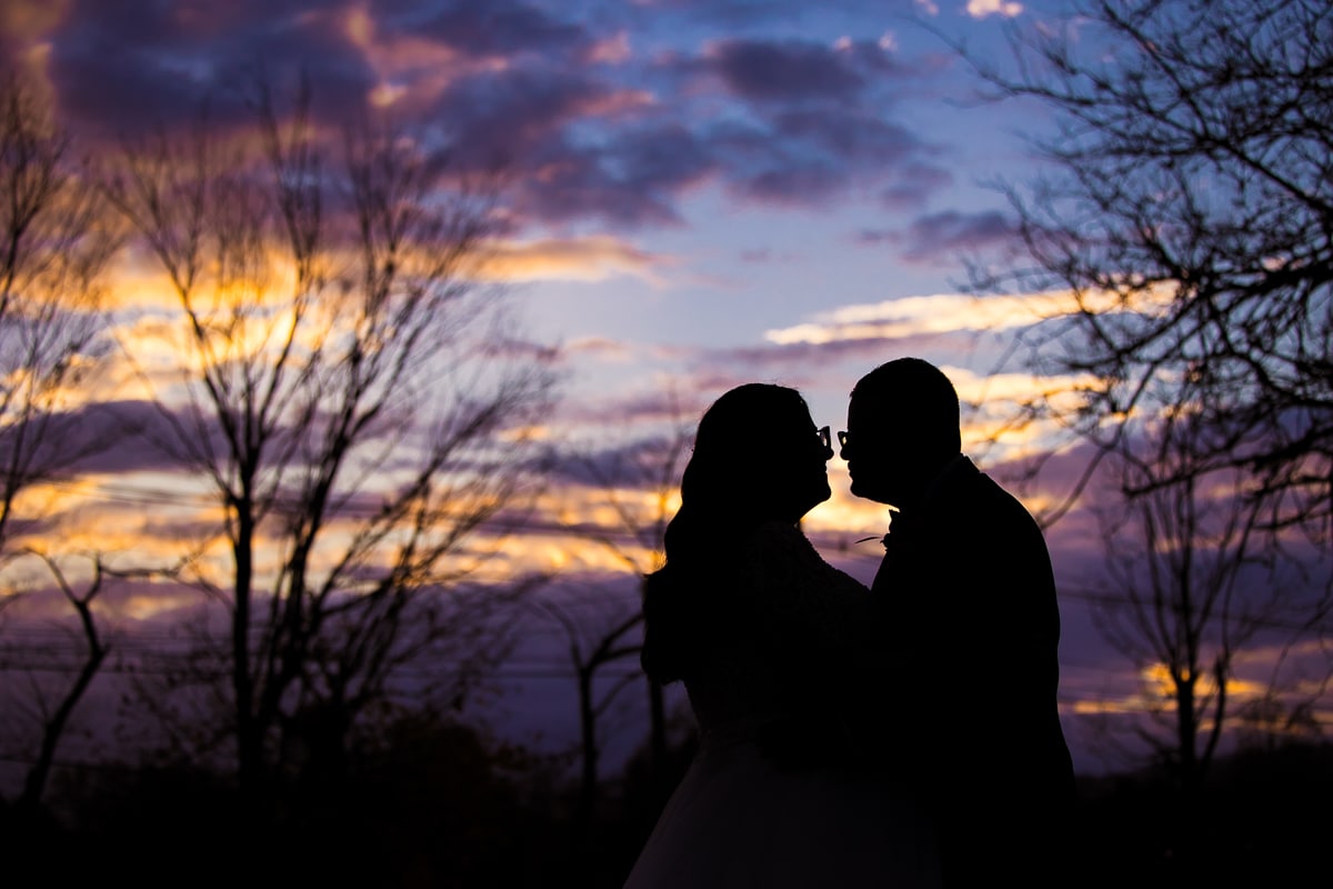 Ryland Inn Wedding Photographer, lisa rhinehart, captures the couple looking at one another as the sun sets behind them in gold, blue and purple tones on their wedding day at the Ryland Inn, NJ