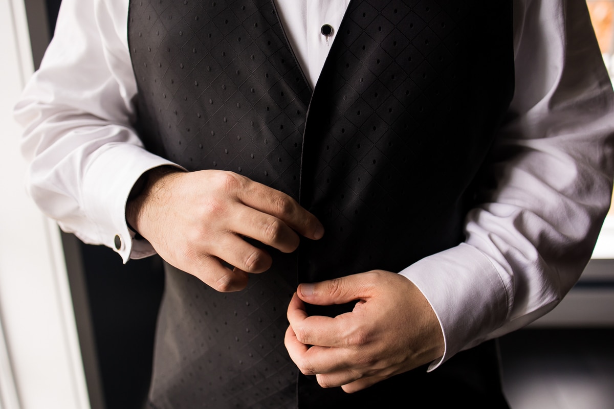 close up image of the groom buttoning up his vest during his preparations before the wedding ceremony at the Ryland Inn 