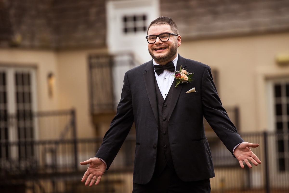 Image of the groom smiling with his hands out as he sees his bride for the first time in her wedding dress before their ceremony at the ryland inn in new jersey 