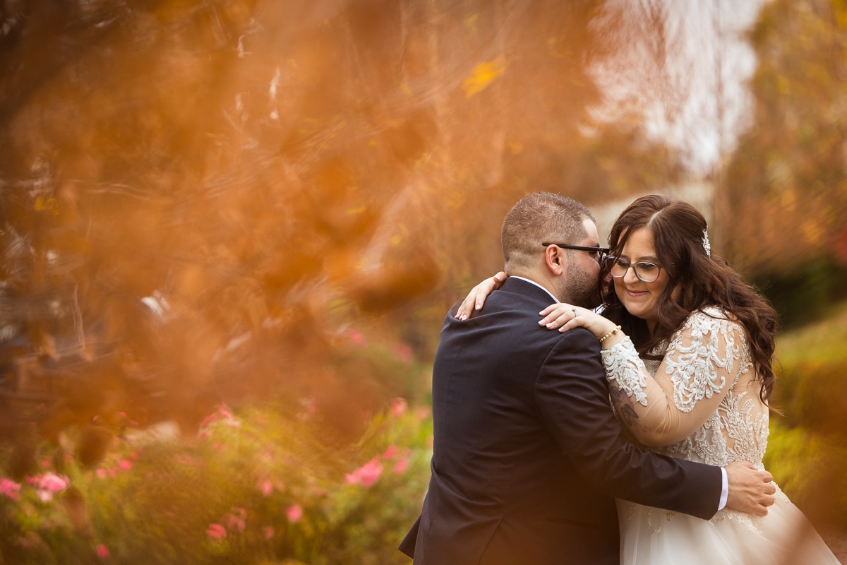 creative, unique, Ryland Inn Wedding Photographer, lisa rhinehart, captures the couple leaning in and hugging one another during their first look with orange leaves surrounding them and creating a unique and creative border around them 