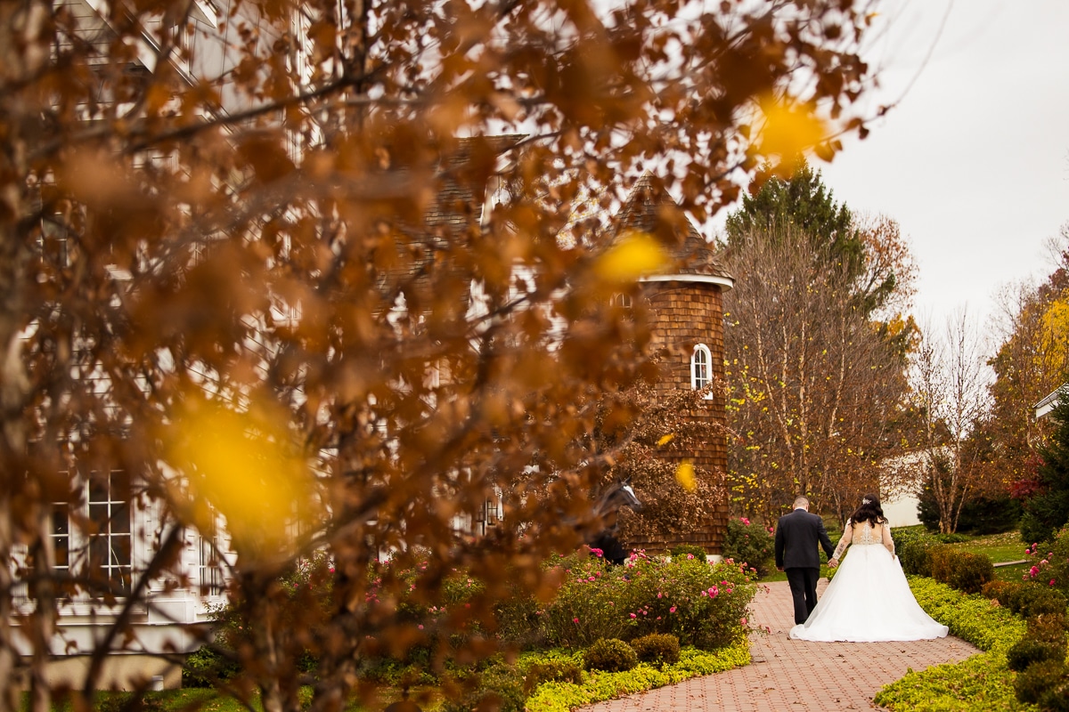 Ryland Inn Wedding Photographer, lisa rhinehart, captures the fall leaves and the bride and the groom walking down a path way as they hold hands together before their fall wedding ceremony at the ryland inn 