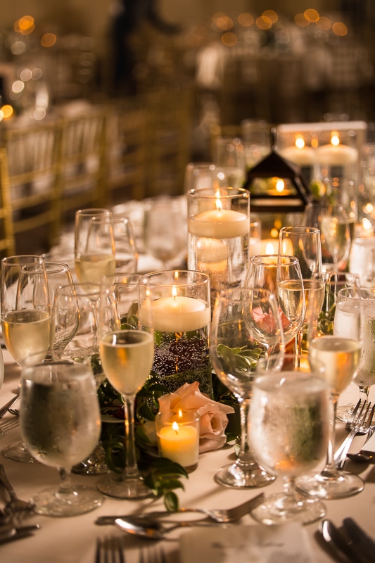 unique, close up image of the table decor and place settings filled with drinks, candles, flowers and more 