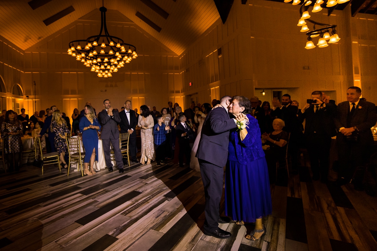 image of the groom dancing on the floor with his mom during the parent dances at the wedding reception in her bright royal blue dress 
