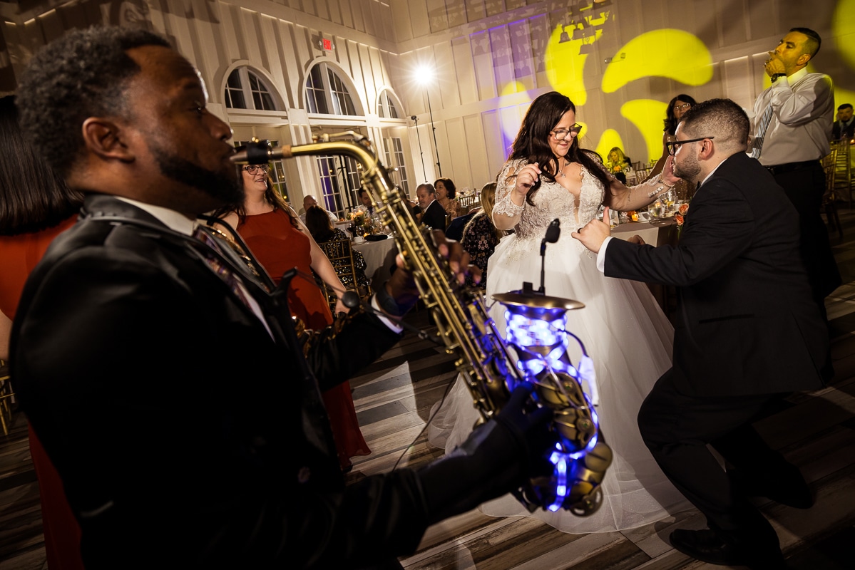 Ryland Inn Wedding Photographer, lisa rhinehart, captures the bride and groom dancing together with the saxophone player playing music in front of them with glowing lights in the base of his instrument 