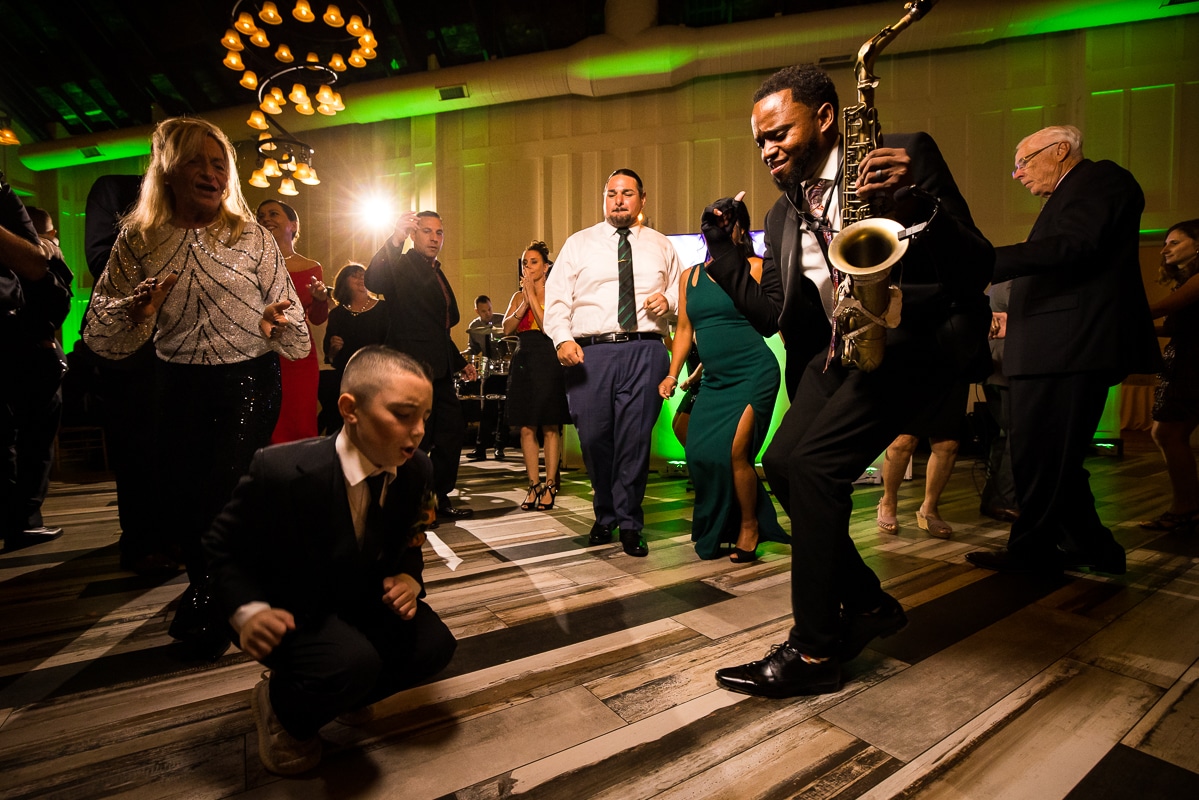 Ryland Inn Wedding Photographer, lisa rhinehart, captures the guests dancing along with a little boy dancing as the saxophone player dances with him also during the wedding reception at the ryland inn 