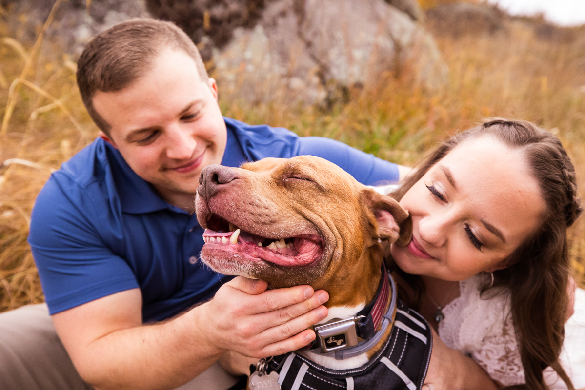 Unique image of the couple smiling with their dog who is also smiling during their Devil's Den Gettysburg Engagement session with rhinehart photography