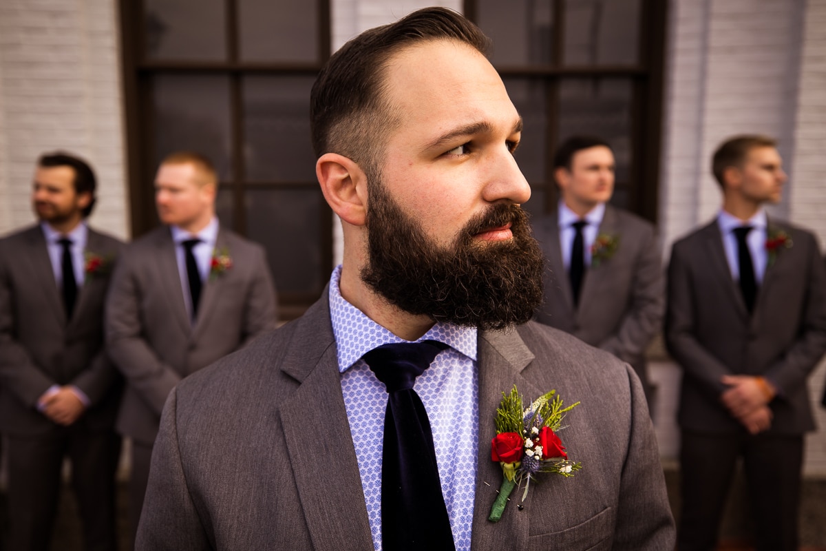 close up portrait of the groom with his groomsmen behind him in outdoor shots before this Gettysburg winter wedding 