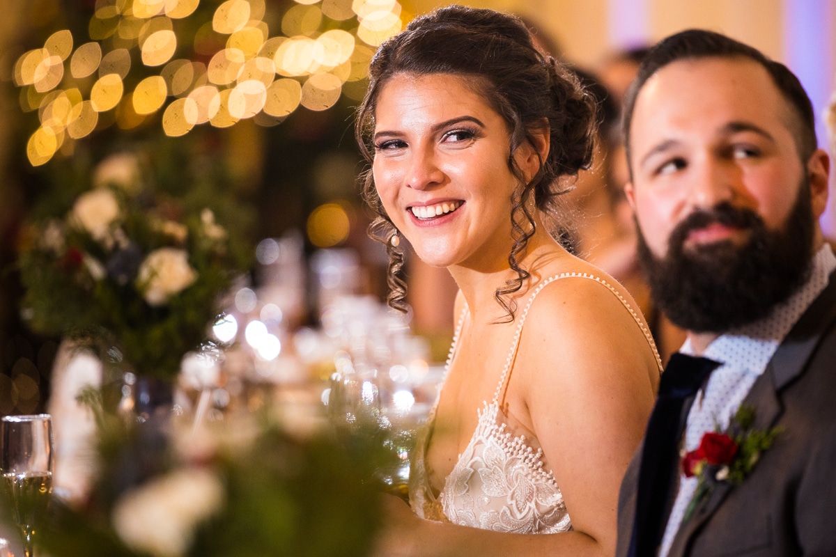 unique, creative image of the bride and groom smiling during their speeches with twinkling Christmas lights behind them during their Gettysburg Hotel Wedding reception 