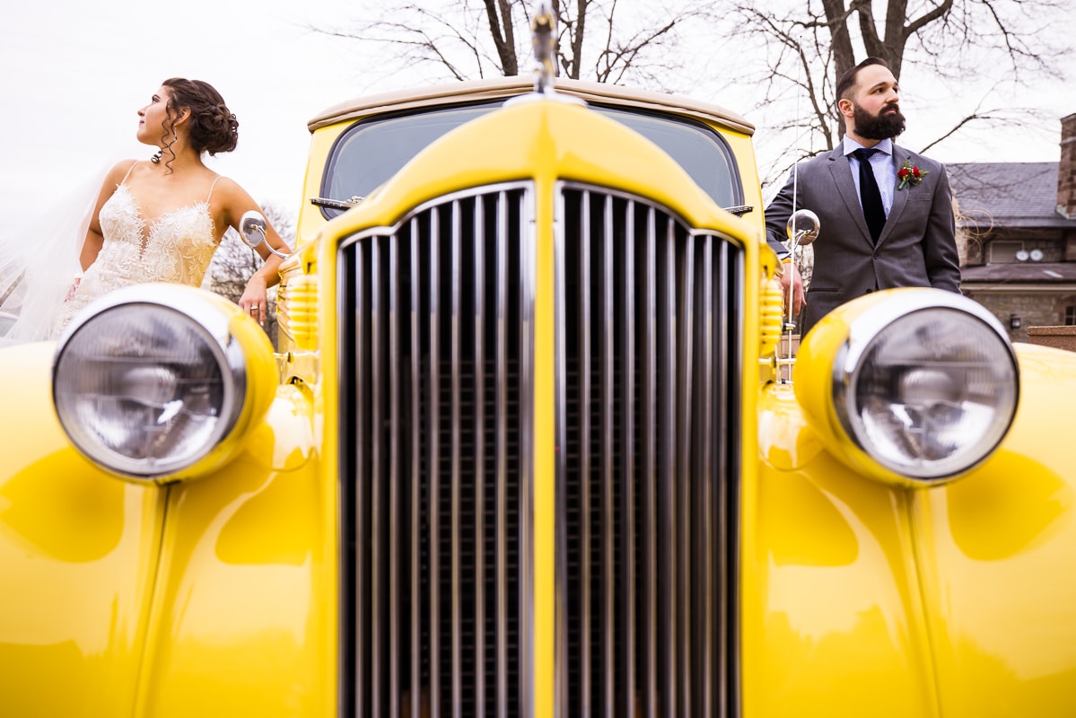 unqiue, creative perspective of the couple with their grandfathers old car during the wedding photos taken by Gettysburg Hotel Wedding photographer, lisa rhinehart at their winter wedding 