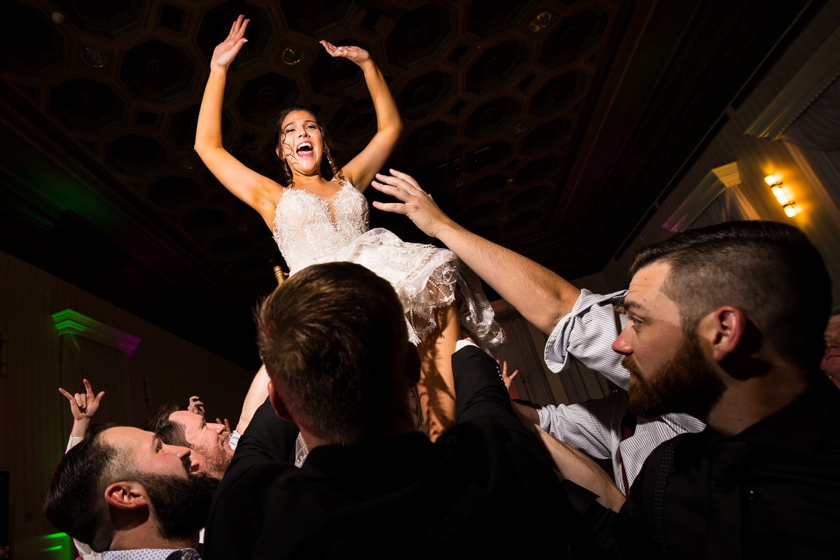 image of the bride with her arms up in the air as she is lifted into the air on a chair during her wedding reception in PA
