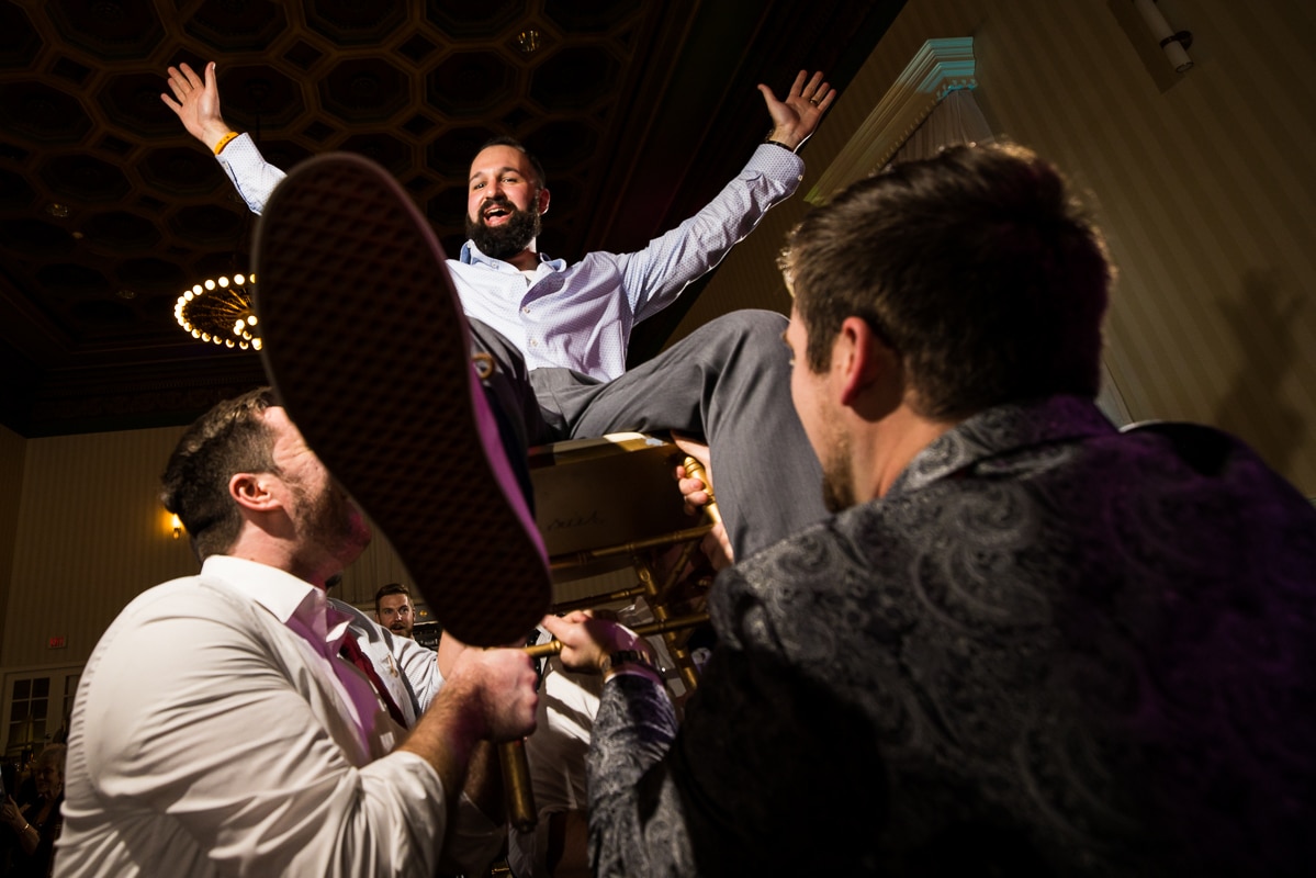 image of the groom being lifted up into the air on a chair during this wedding reception in PA 