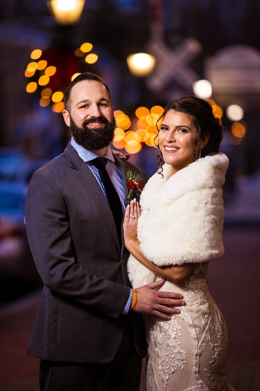 Gettysburg Hotel Wedding photographer, lisa rhinehart, captures this creative, colorful, fun image of the bride and groom smiling at the camera with Christmas lights behind them during their winter wedding 