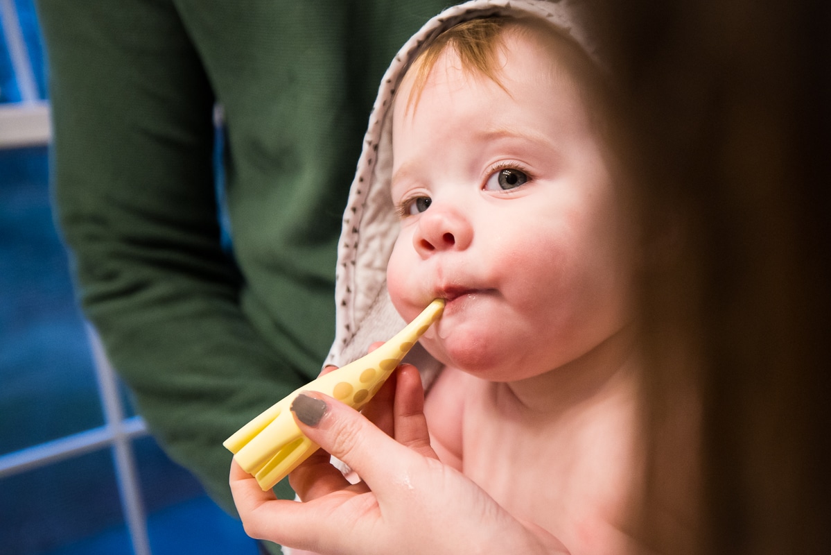 New Cumberland Family photographer, Lisa Rhinehart, captures a creative angle of the baby getting her teeth brushed after her bathtime before bed with her giraffe toothbrush