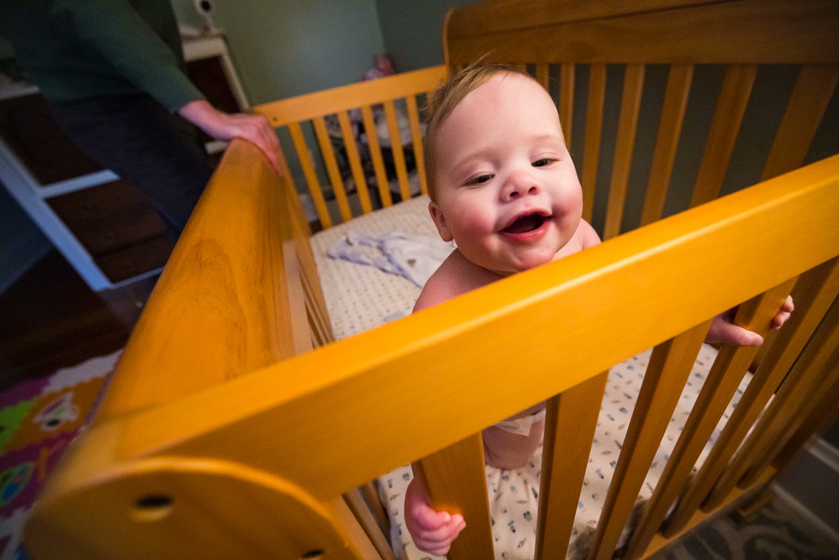 creative family photographer, lisa rhinehart, captures this baby as she is in her crib smiling out over the side before bedtime