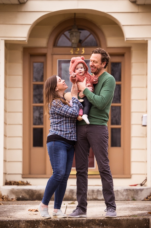 New Cumberland Family photographer, Lisa Rhinehart, captures the family loving their baby as they stand outside of their home in Pennsylvania
