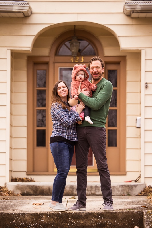 central pa family photographer captures the family smiling and looking at the camera as they stand outside of their home 