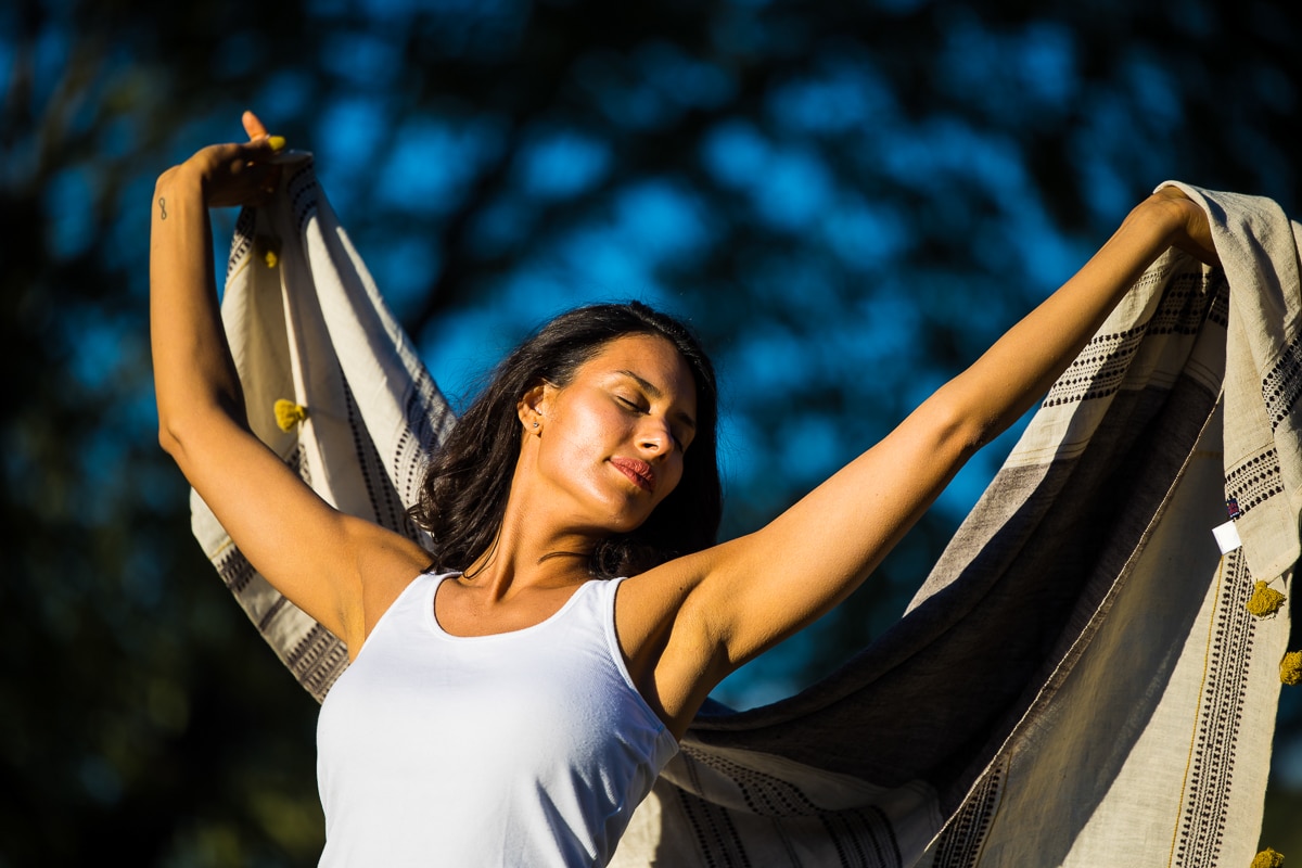 image of a woman holding her arms up with her blanket behind her as she closes her eyes and enjoys the sun and nature during her business branding session in Chambersburg pa 