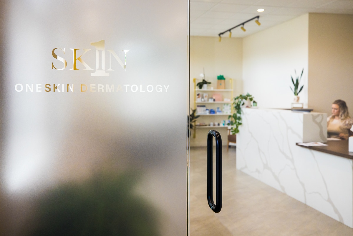 commerical branding picture of the unique entrance to OneSkin Dermatology in Chambersburg, PA which shows the door and the front desk worker 