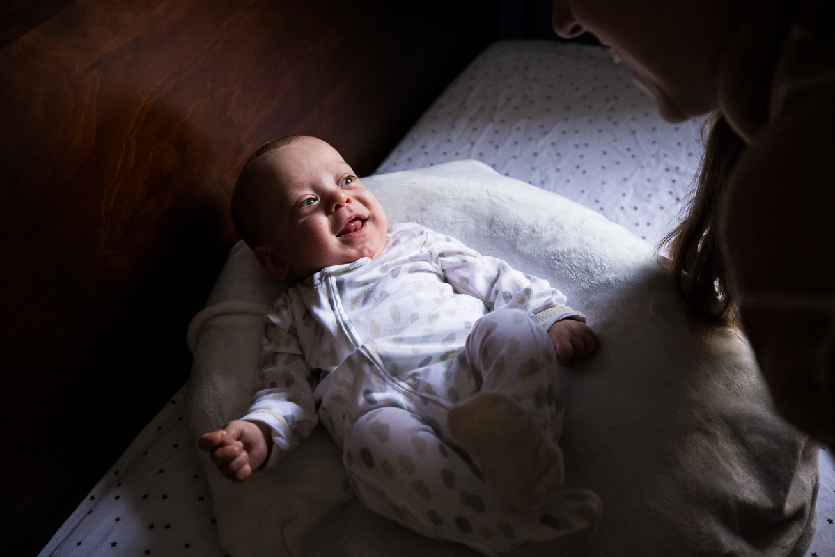Rhinehart photography captures this newborn baby as he wakes up from his nap smiling at mom before their portrait session 