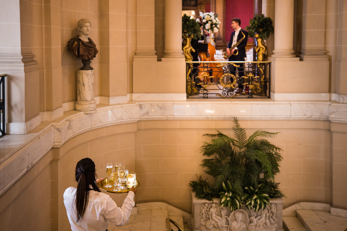 rhinehart photography captures the elegant details inside of this Washington dc wedding venue as waitresses are bringing trays down the staircase and the band is setting up 