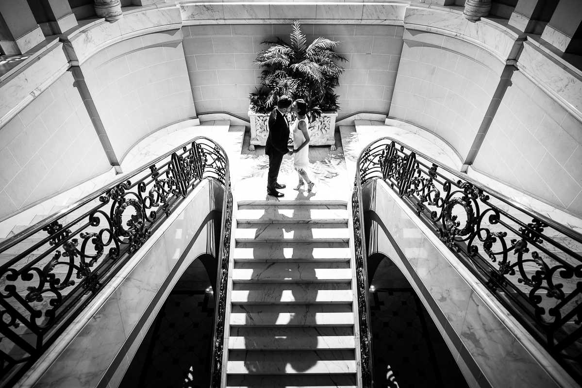 Perry Belmont House Wedding Photographer, rhinehart photography, captures this elegant, timeless black and white image of the couple from this unique and creative perspective as they stand on the grand staircase kissing one another 