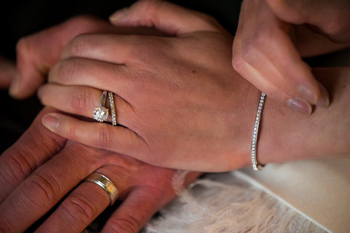 wedding photographer, lisa rhinehart, captures the bride and grooms hands together showing off their rings and other jewelry 