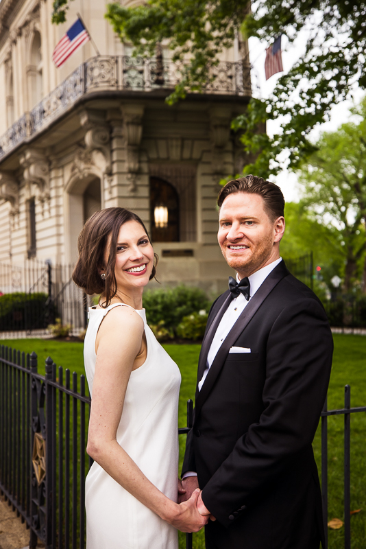 rhinehart photography captures this traditional image of the couple as they stand facing one another, holding hands and looking at the camera outside of their Washington dc wedding venue 