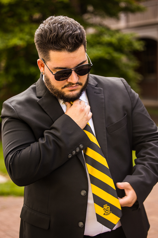 Shippensburg senior portrait photographer, lisa rhinehart, captures this image of graduating senior as he adjusts his tie while wearing his sunglasses for his senior pictures 