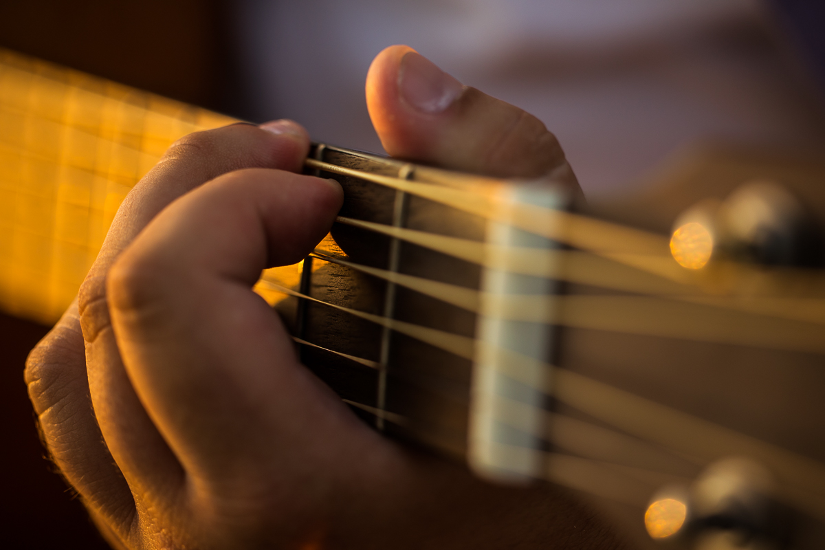 Close up image of this seniors fingers playing on the strings on the guitar during this authentic senior portrait session 