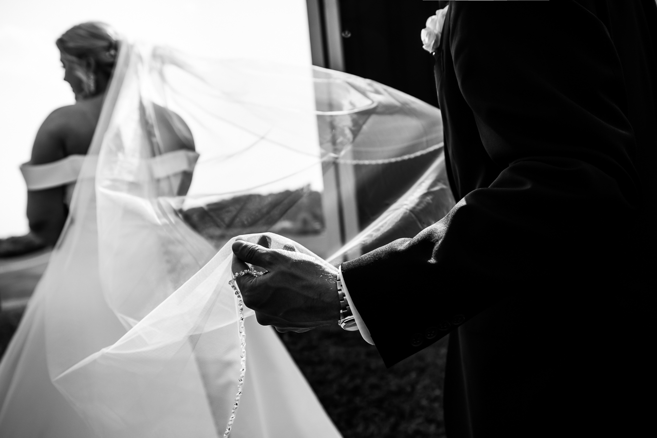 Middleburg Barn Wedding Photographer, lisa rhinehart, captures this black and white image of the groom holding the brides veil during their portraits at their virginia wedding 