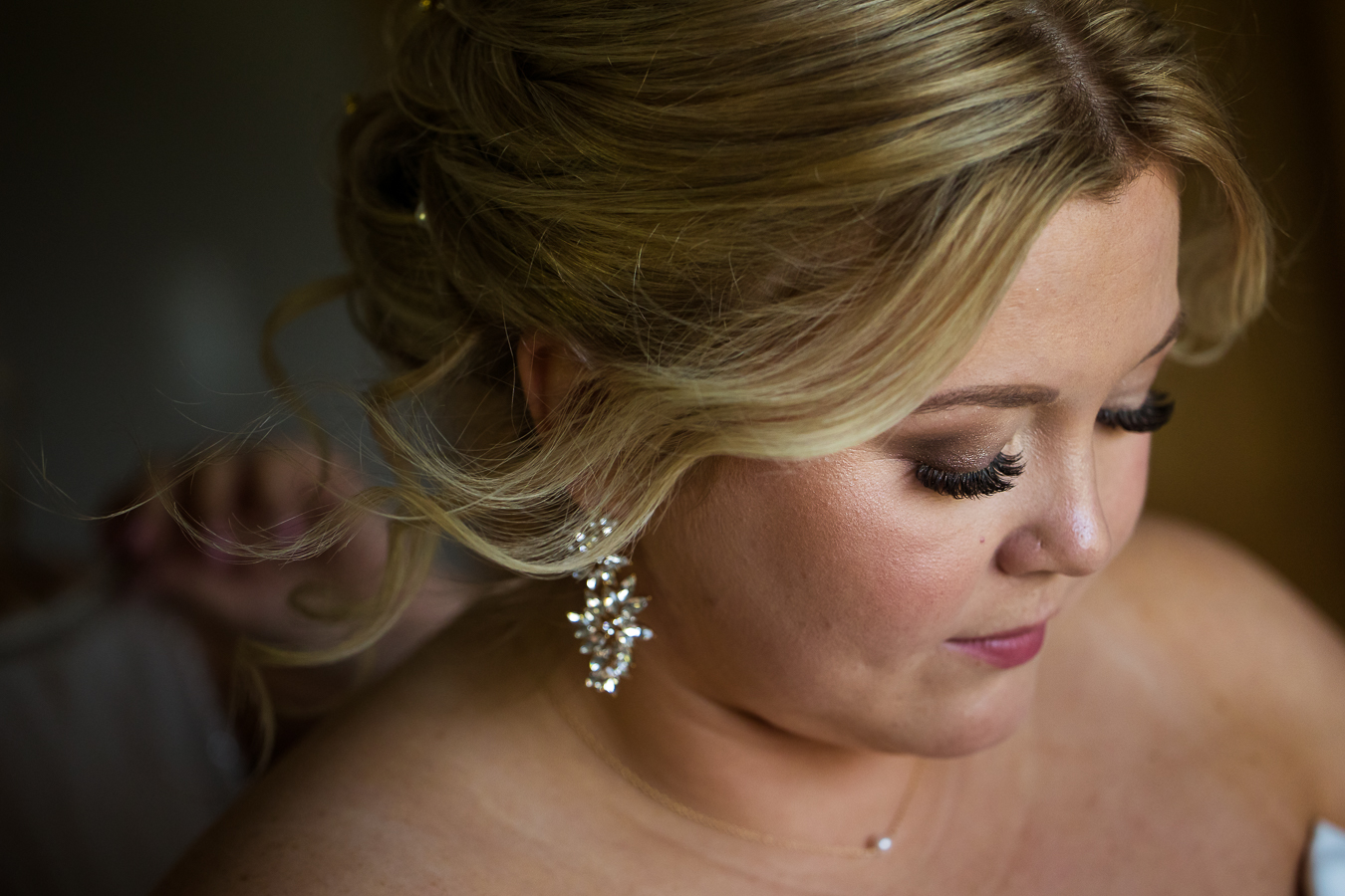 Close up image of the brides earring and her curly updo during the wedding preparation part of her wedding day in Virginia 