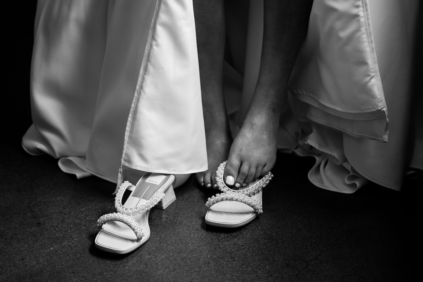 Wedding photographer, lisa rhinehart, captures this black and white image of the bride putting on her pearl stoned heels before her wedding ceremony at Middleburg barn