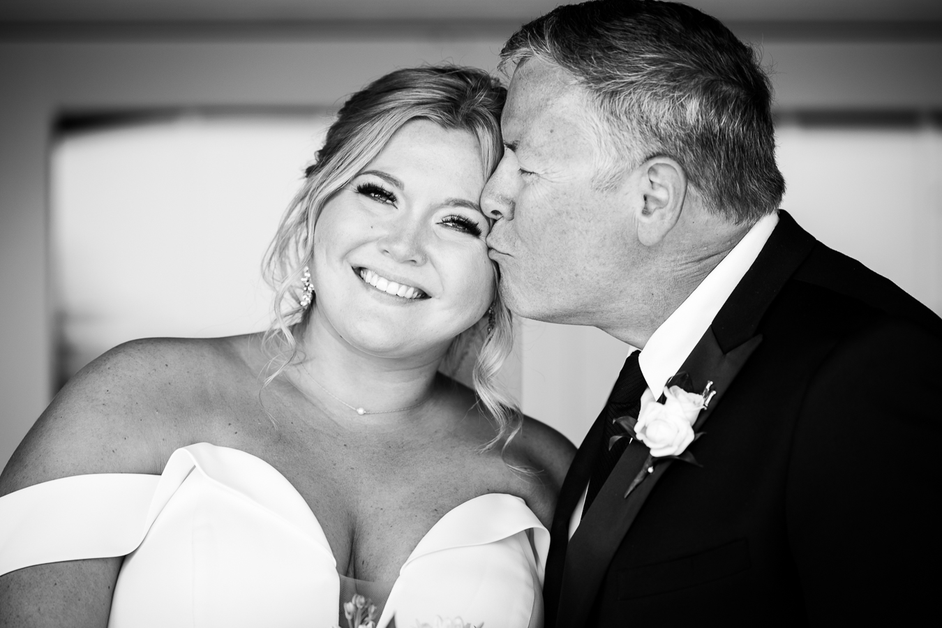 Creative, Authentic wedding photographer, lisa rhinehart, captures this black and white image of the bride with her father as she leans into him while he kisses her cheek during the father daughter first look before the wedding ceremony at Middleburg Barn 