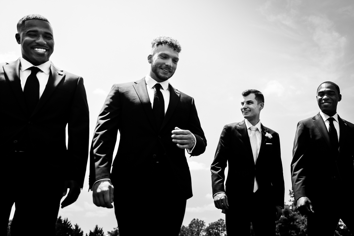 black and white image of the groom and his groomsmen laughing and smiling as they walk outside before the wedding ceremony at middleburg barn 