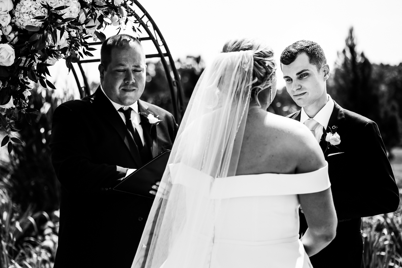 Virginia wedding photographer, lisa rhinehart, captures this black and white image of the groom looking into his brides eyes as they stand at the end of the aisle together during their wedding ceremony 