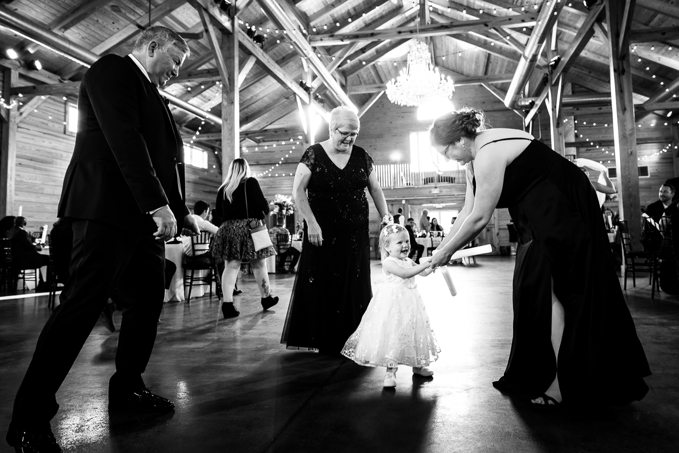 authentic Wedding Photographer, lisa rhinehart, captures this black and white image of guests dancing together with the flowergirl during the wedding reception 