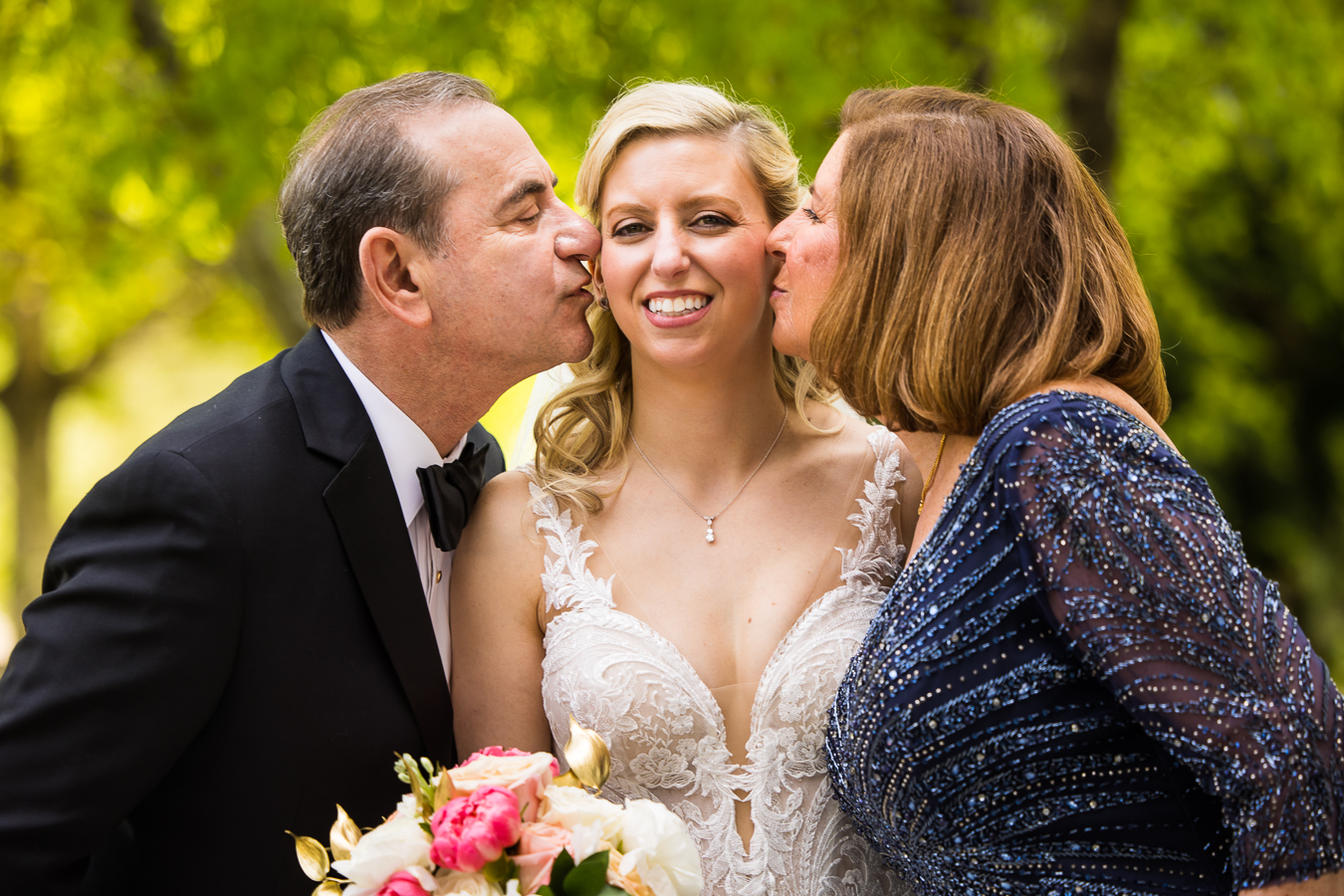  lisa rhinehart, captures this candid, fun, authentic image of the bride smiling between her parents as they kiss her on the cheek before her wedding ceremony at the Palace