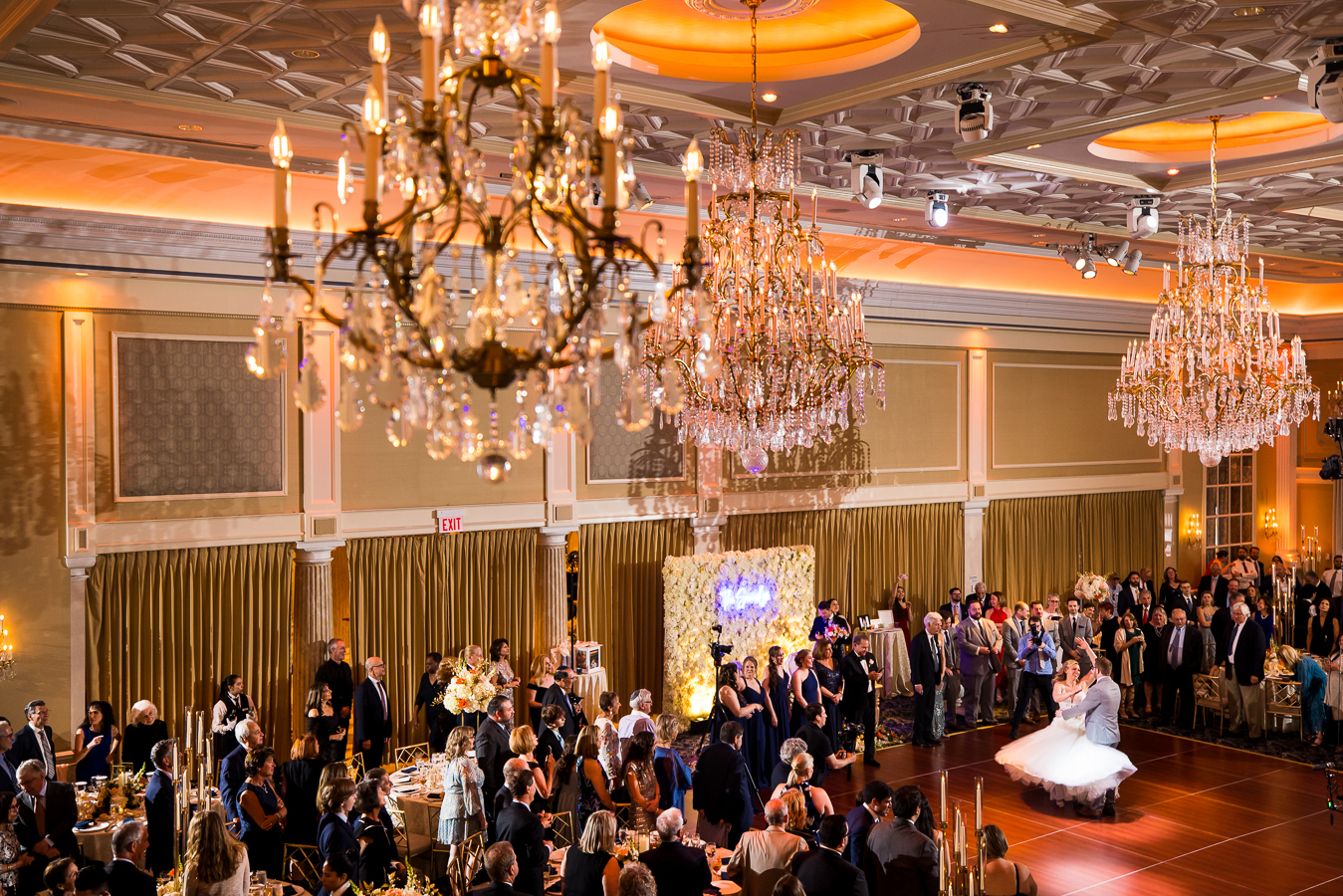 creative NJ Wedding Photographer, lisa rhinehart, captures this unique, creative image of the bride and groom's first dance from on the balcony which captured all of their guests and family standing and cheering for them during their reception at the palace at somerset 
