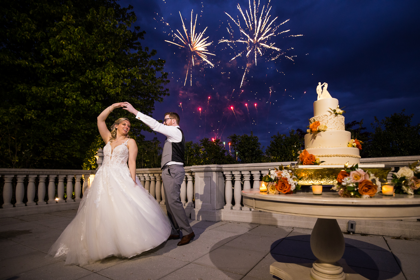 creative NJ Wedding Photographer, lisa rhinehart, captures this fun, vibrant image of the bride and groom as they twirl one another with fireworks in the background during their palace at somerset wedding reception in new jersey 