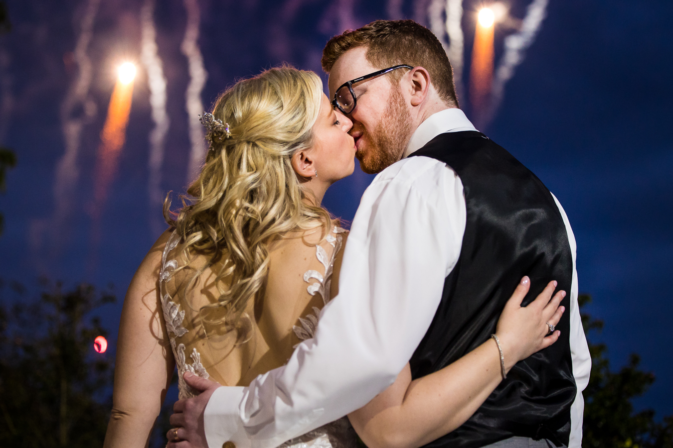image of the bride and groom as they share a kiss while watching the fireworks at their palace of somerset wedding reception