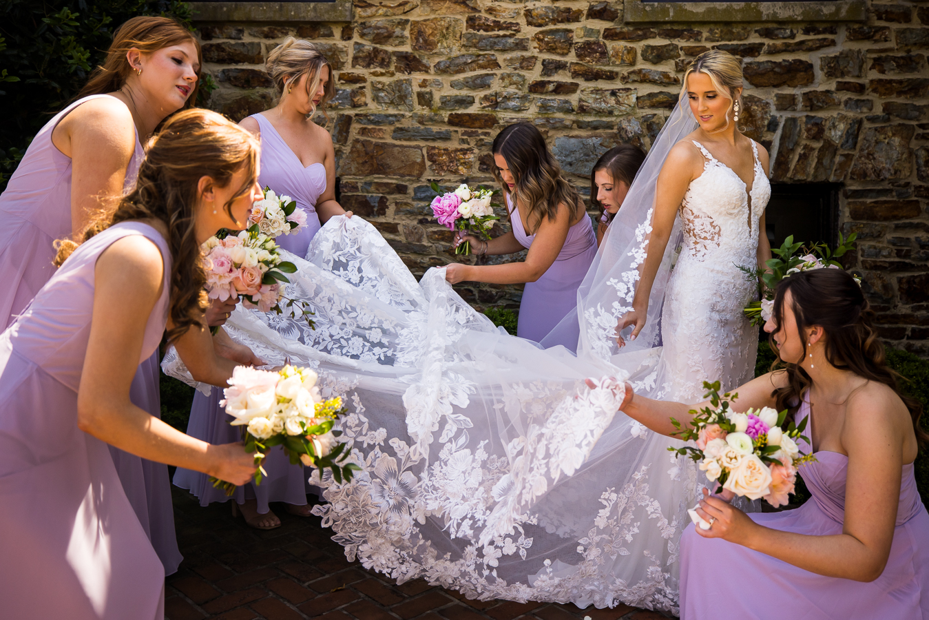 wedding photographer, lisa rhinehart, captures this image of the bridesmaids helping lay out the brides dress before their bridal party photos