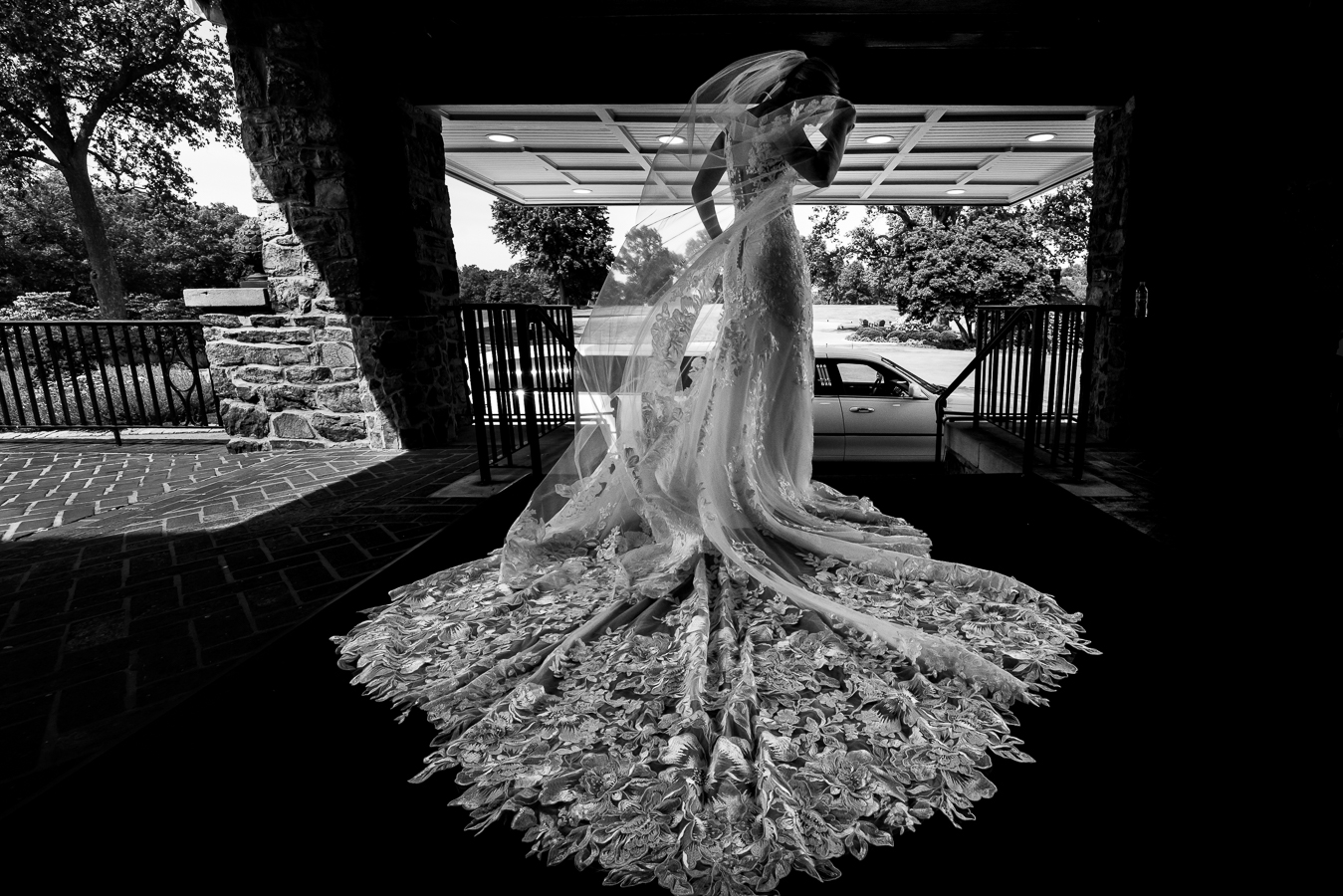 creative, classic black and white image of the bride in her wedding gown with her train spread out before her wedding ceremony