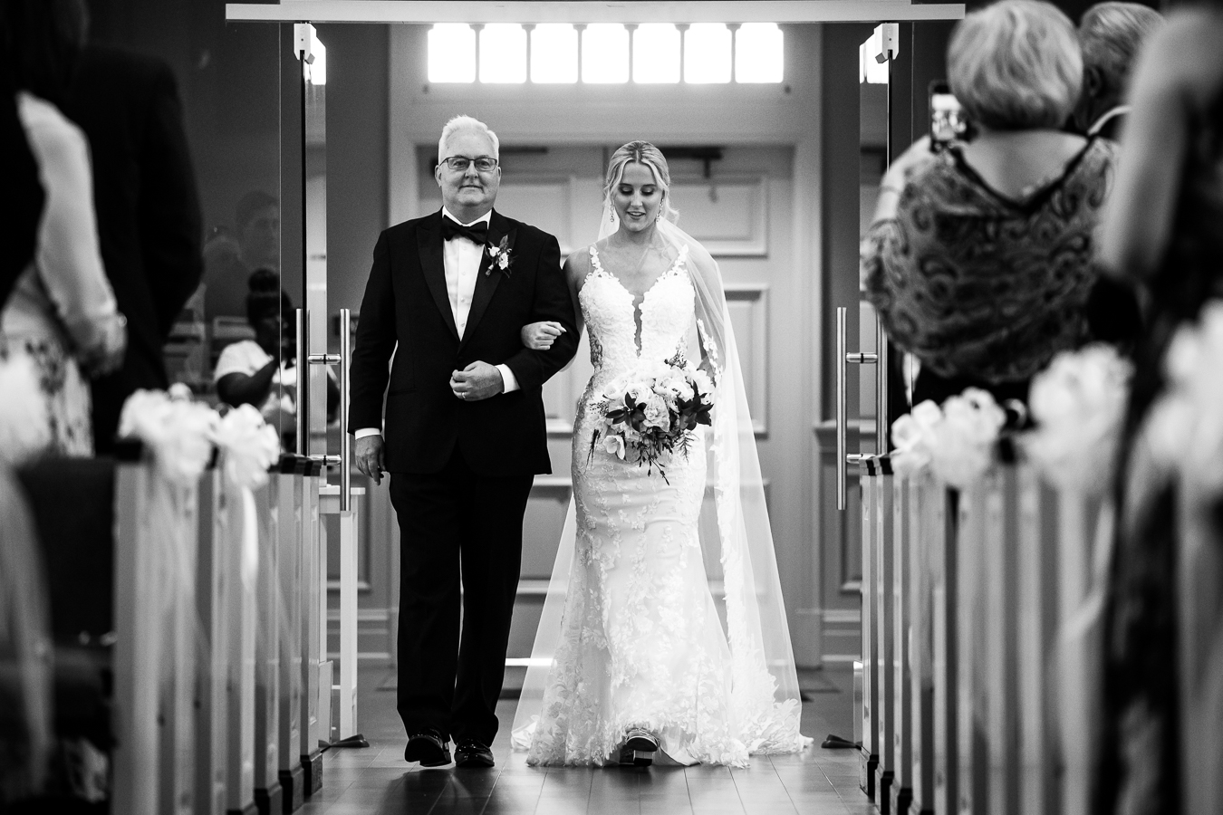 st paul lutheran church wedding photographer, lisa rhinehart, captures this black and white image of the bride and her dad as they walk down the aisle together for the wedding ceremony 