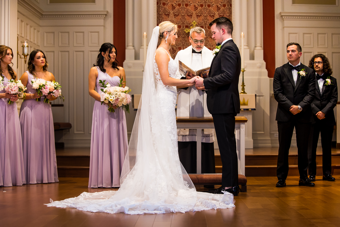 best pa wedding photographer, lisa rhinehart, captures this traditional image of the bride and groom holding hands during their wedding ceremony with their wedding party behind them 