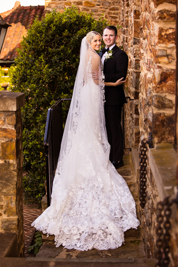 pa wedding photographer, lisa rhinehart, captures this traditional image of the bride and groom embracing one another on the staircase with the brides dress and train laying over the steps 