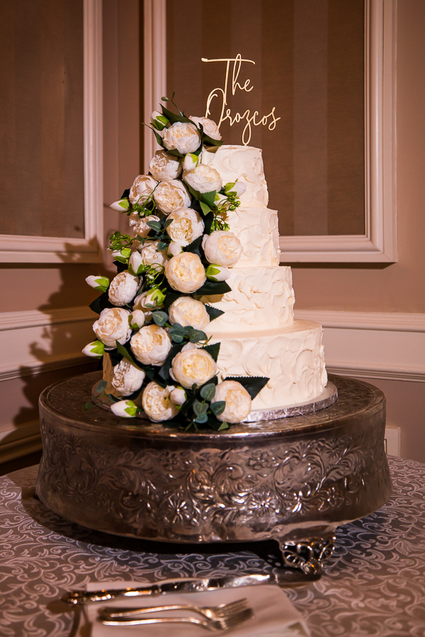 traditional image of the wedding cake with white flowers down the side and the couples name on the top at the wedding reception