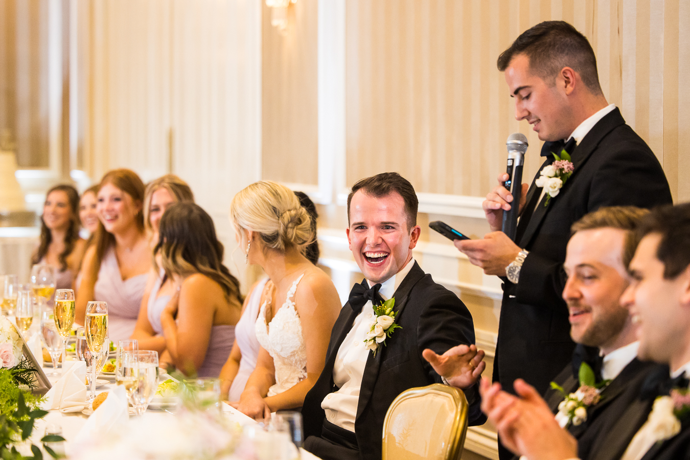image of the groom laughing with his groomsmen as they give speeches during the wedding reception at the country club of york