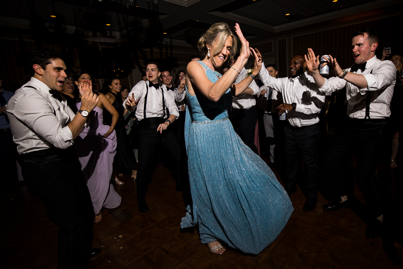 creative, fun image of the brides mom dancing on the dance floor with her hands in the air during the wedding reception