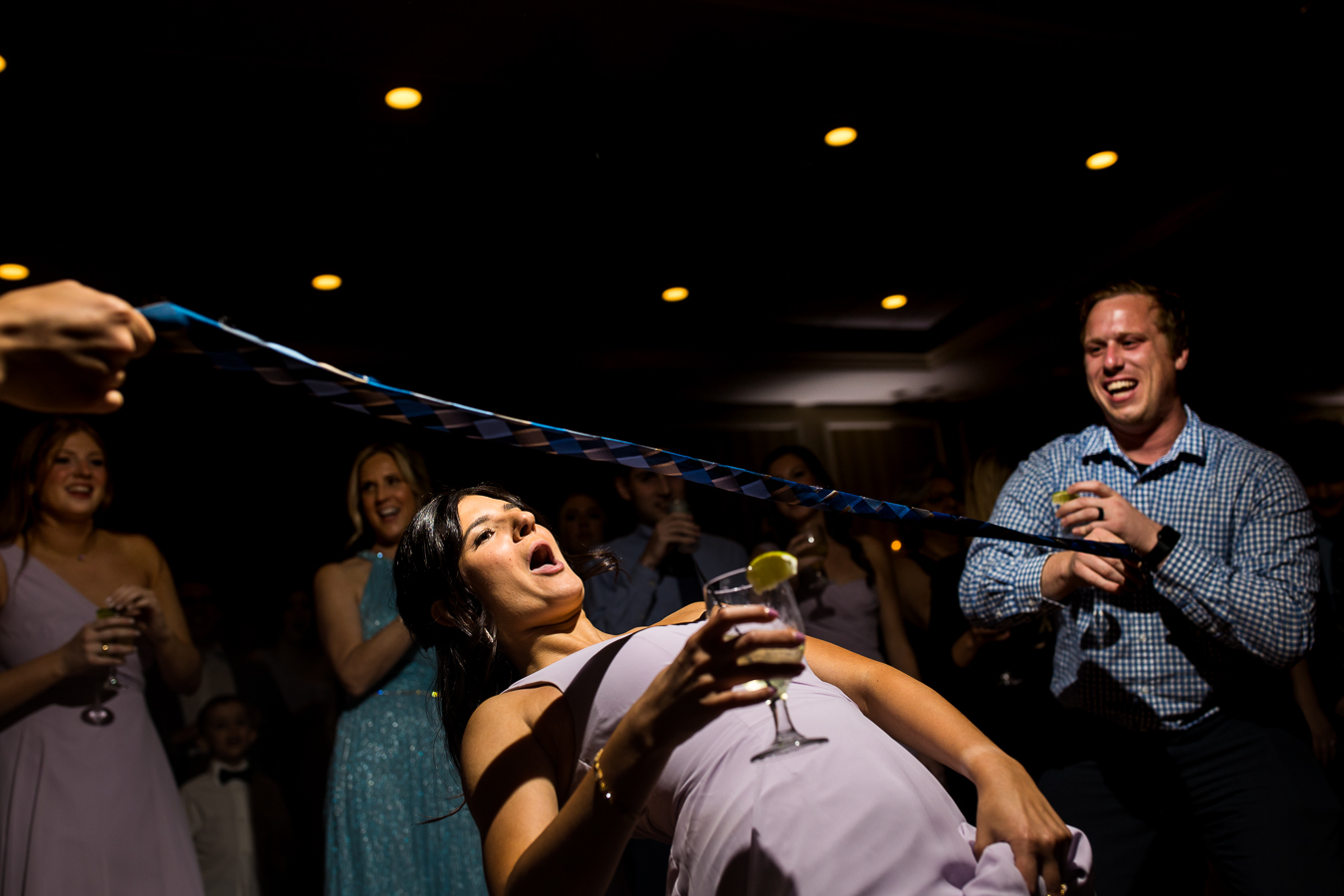 country club of york wedding photographer, lisa rhinehart, captures this fun image of a bridesmaid playing limbo with a drink in her hand at this wedding reception
