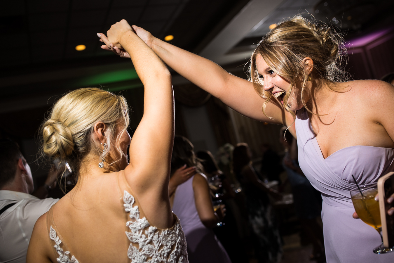 best pa wedding photographer, lisa rhinehart, captures this image of the bride holding hands with a bridesmaid as they dance together 